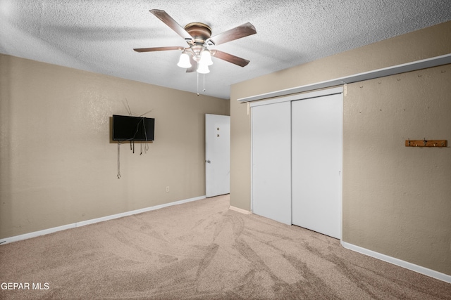 unfurnished bedroom with light carpet, a textured ceiling, a closet, and baseboards