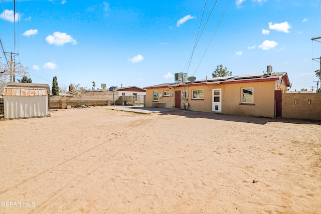 back of house with stucco siding, a fenced backyard, and central air condition unit