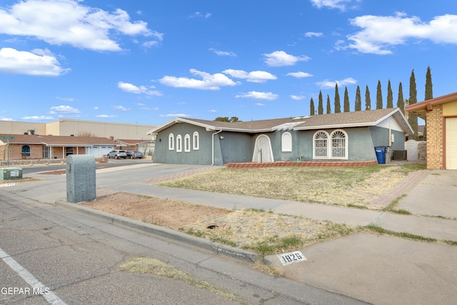 single story home featuring central AC unit, concrete driveway, and stucco siding