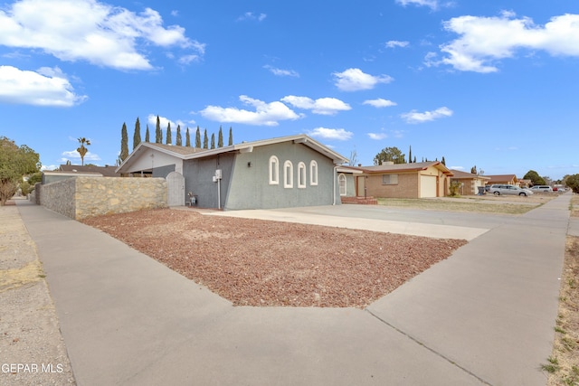 ranch-style home featuring fence, concrete driveway, and stucco siding