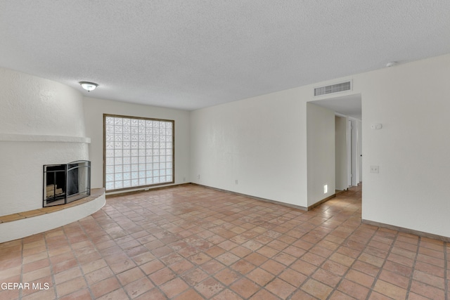 unfurnished living room with baseboards, visible vents, a fireplace with raised hearth, and a textured ceiling