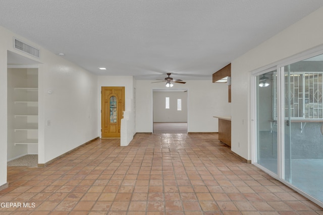 unfurnished room featuring a textured ceiling, ceiling fan, visible vents, built in features, and baseboards