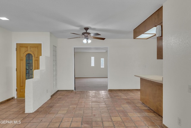 empty room featuring ceiling fan and baseboards