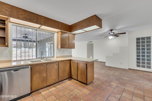 kitchen with light countertops, stainless steel dishwasher, brown cabinetry, a sink, and a peninsula