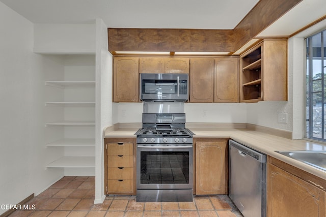 kitchen with light countertops, appliances with stainless steel finishes, open shelves, and brown cabinets