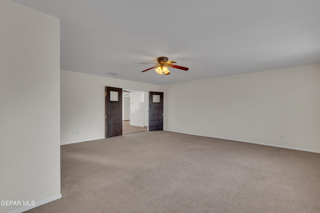 empty room featuring light carpet, a ceiling fan, and baseboards