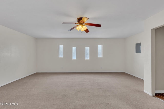 carpeted spare room with a ceiling fan, electric panel, and baseboards