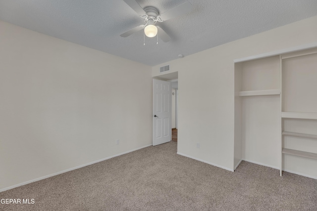 unfurnished bedroom featuring a textured ceiling, carpet flooring, visible vents, and baseboards