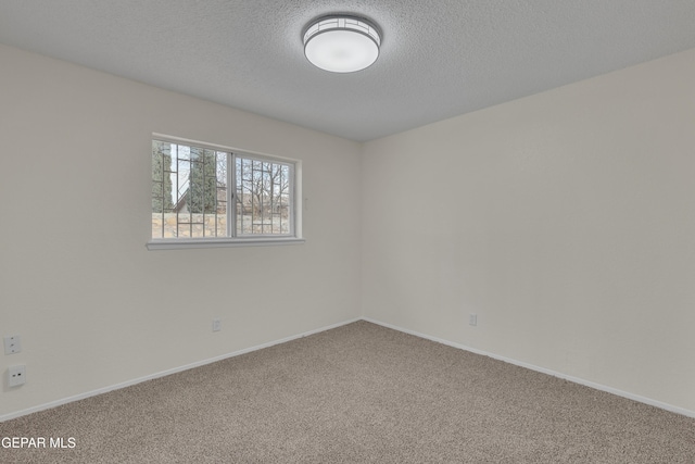 empty room with a textured ceiling, carpet floors, and baseboards