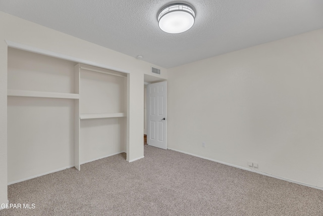 unfurnished bedroom with baseboards, visible vents, a textured ceiling, carpet flooring, and a closet