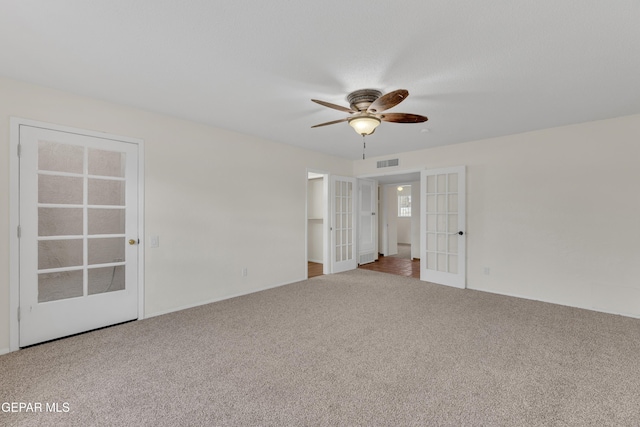 carpeted empty room featuring visible vents, french doors, and a ceiling fan