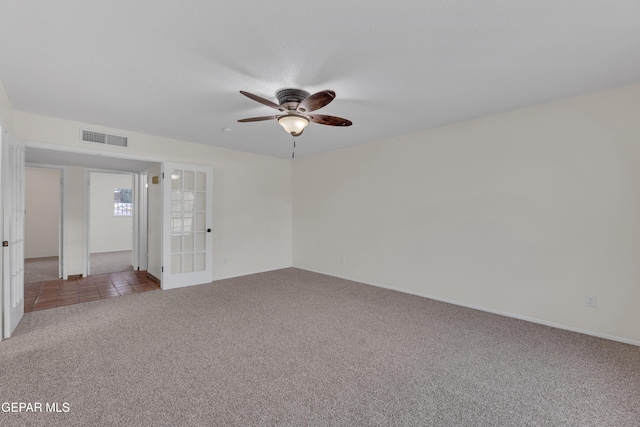 empty room featuring french doors, light colored carpet, visible vents, light tile patterned flooring, and ceiling fan