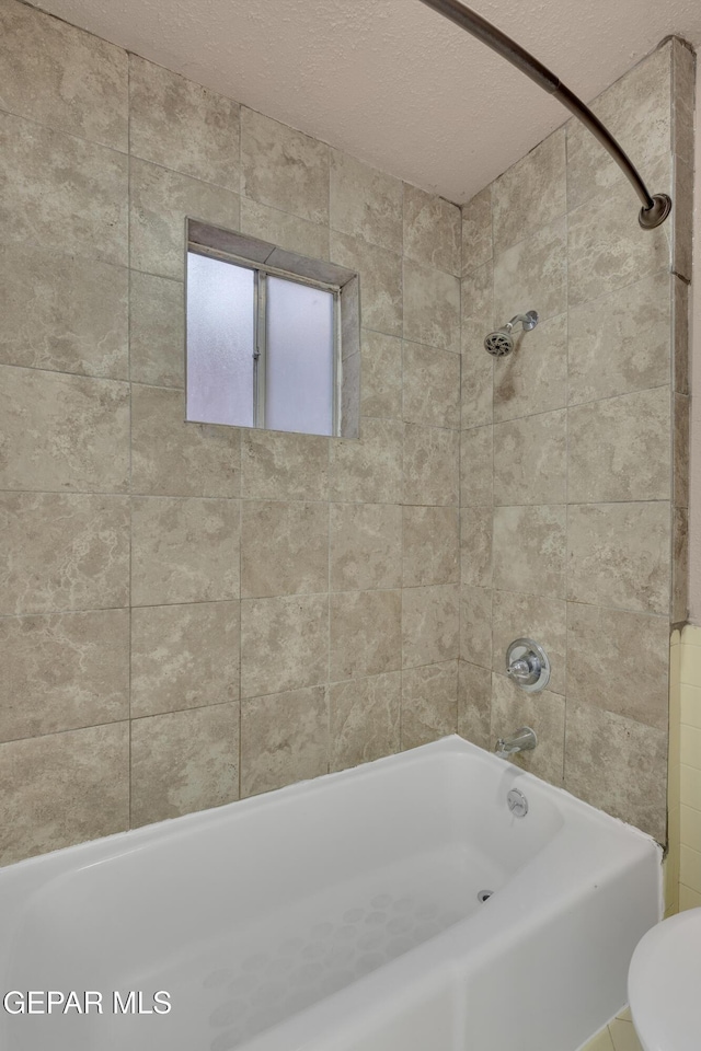 full bath with toilet, shower / tub combination, and a textured ceiling