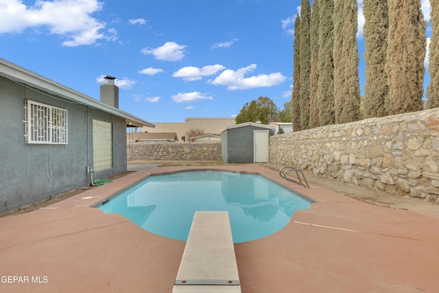 view of pool featuring a fenced backyard, an outdoor structure, a diving board, a fenced in pool, and a shed