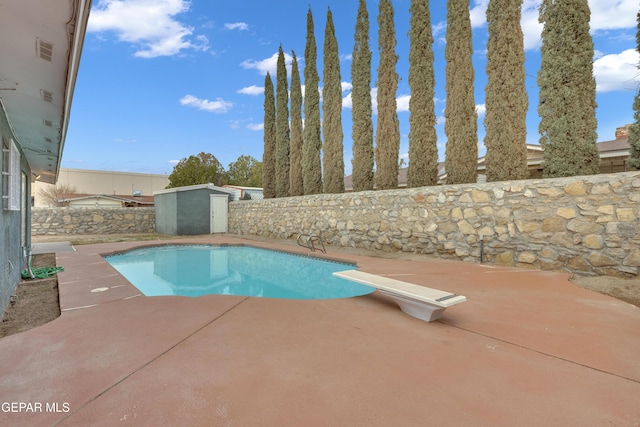 view of pool with an outbuilding, a fenced backyard, a diving board, a fenced in pool, and a patio area