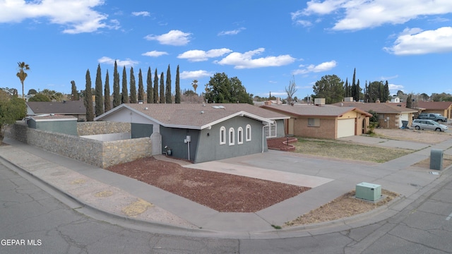 ranch-style home with a garage, a residential view, concrete driveway, and stucco siding