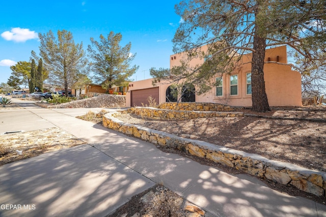 view of front of home with concrete driveway, an attached garage, and stucco siding