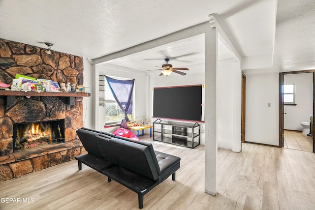 living room with a textured ceiling, a fireplace, a wealth of natural light, and light wood-style floors