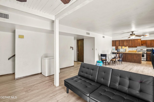 living area featuring baseboards, visible vents, ceiling fan, and light wood finished floors