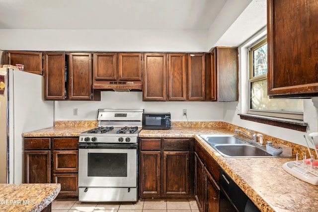 kitchen with under cabinet range hood, stainless steel range with gas cooktop, light countertops, and a sink