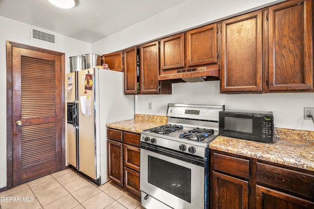 kitchen featuring gas range oven, visible vents, light tile patterned flooring, black microwave, and under cabinet range hood