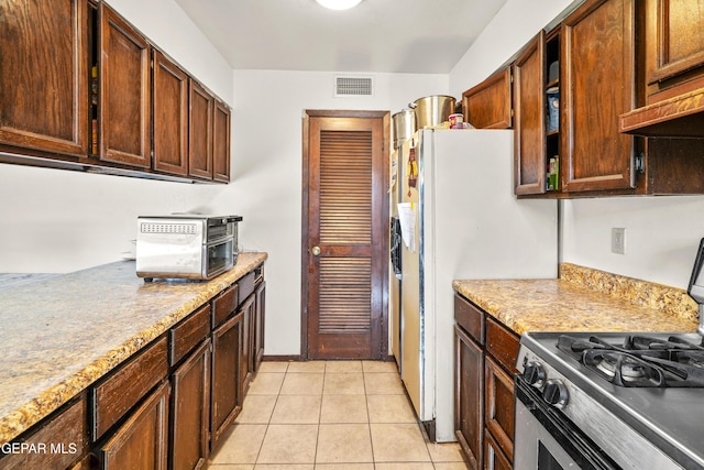 kitchen featuring stainless steel gas stove, visible vents, and light tile patterned flooring