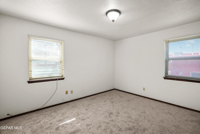 carpeted spare room with a textured ceiling and baseboards