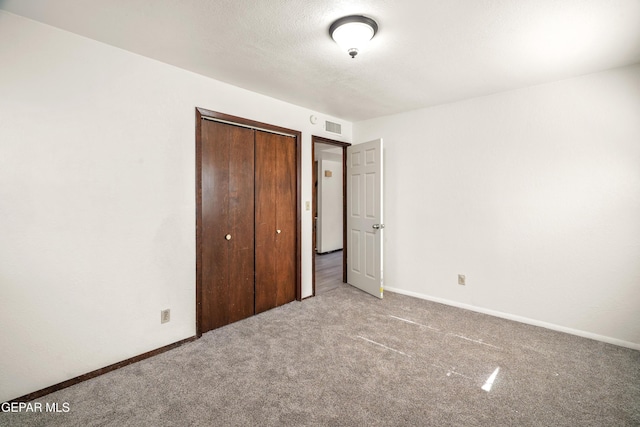 unfurnished bedroom featuring a closet, carpet flooring, visible vents, and baseboards