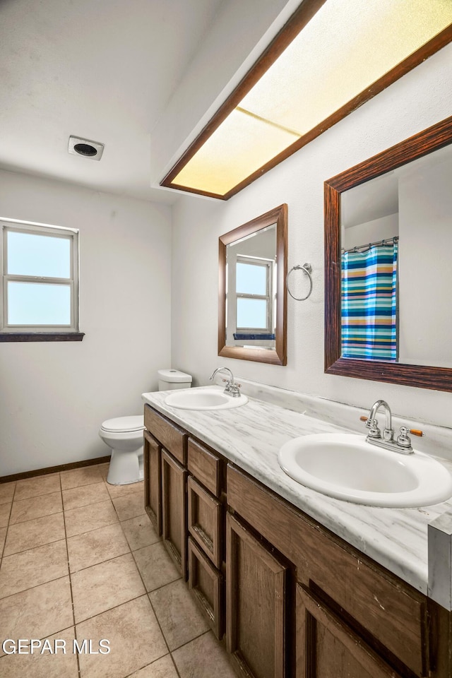 full bath with tile patterned floors, a sink, toilet, and double vanity