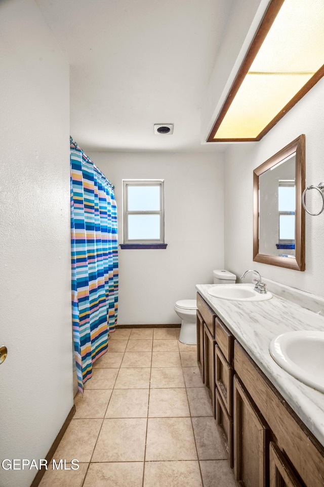 bathroom featuring tile patterned flooring, a sink, toilet, and double vanity