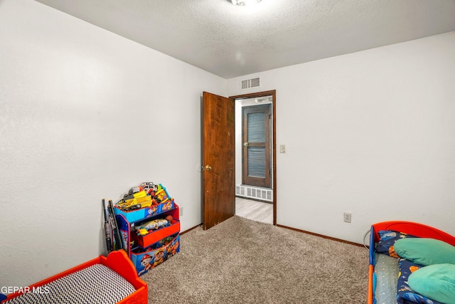 playroom with light carpet, a textured ceiling, visible vents, and baseboards