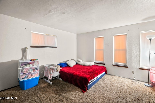 bedroom featuring a textured ceiling, a textured wall, and carpet