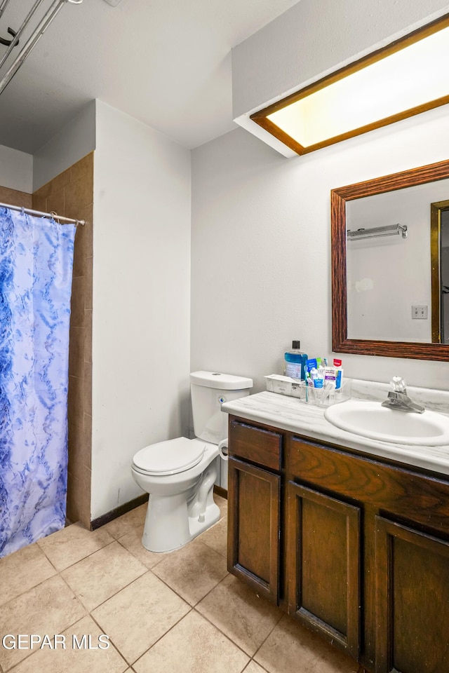 bathroom with toilet, vanity, a shower with curtain, baseboards, and tile patterned floors