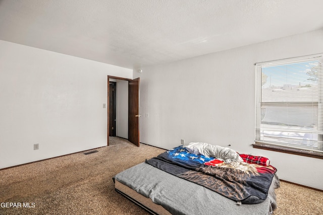 bedroom with light carpet, visible vents, and a textured ceiling