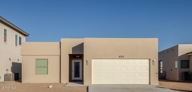 view of front facade featuring concrete driveway, central air condition unit, an attached garage, and stucco siding