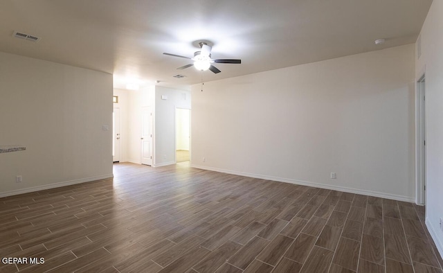 unfurnished room with a ceiling fan, wood finish floors, visible vents, and baseboards