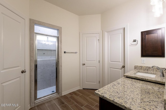 bathroom with a shower stall, wood tiled floor, baseboards, and vanity