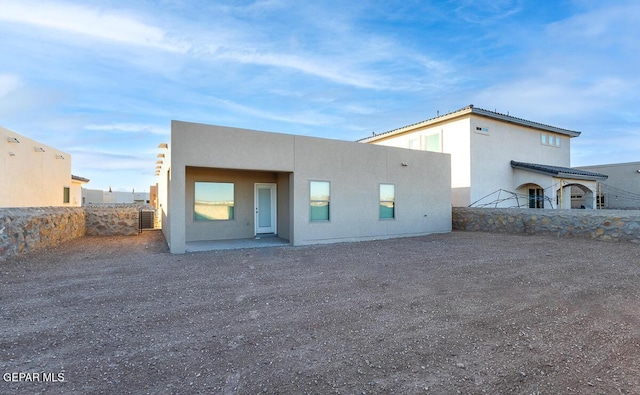 view of front of property featuring a patio, central AC, fence, and stucco siding