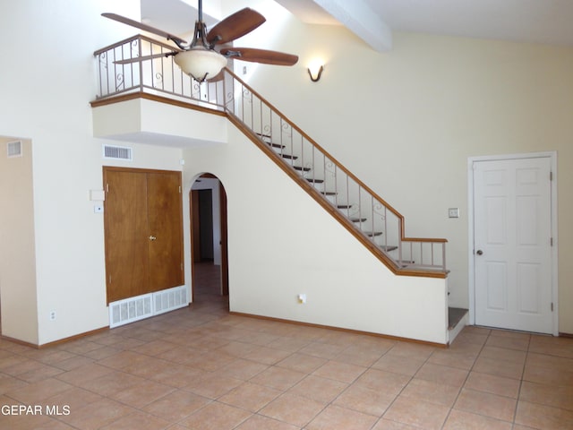 unfurnished living room featuring arched walkways, beam ceiling, visible vents, ceiling fan, and high vaulted ceiling