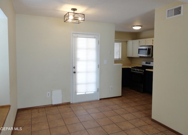 kitchen featuring light tile patterned floors, visible vents, white cabinetry, light countertops, and appliances with stainless steel finishes