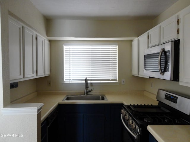 kitchen with light countertops, appliances with stainless steel finishes, a sink, and white cabinets