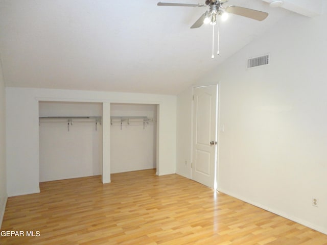 unfurnished bedroom with lofted ceiling, ceiling fan, light wood-style flooring, visible vents, and two closets