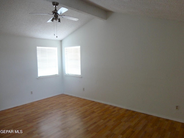 unfurnished room with vaulted ceiling with beams, a textured ceiling, and wood finished floors