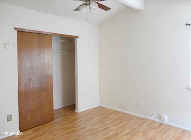 unfurnished bedroom featuring light wood-style floors, a closet, a textured ceiling, and lofted ceiling with beams