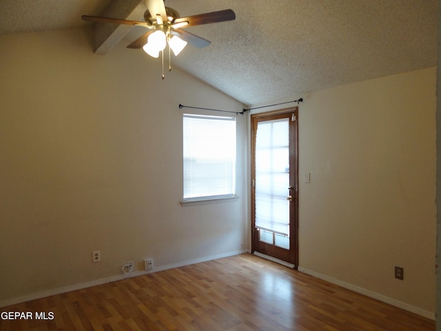 empty room featuring light wood finished floors, baseboards, vaulted ceiling, and a textured ceiling