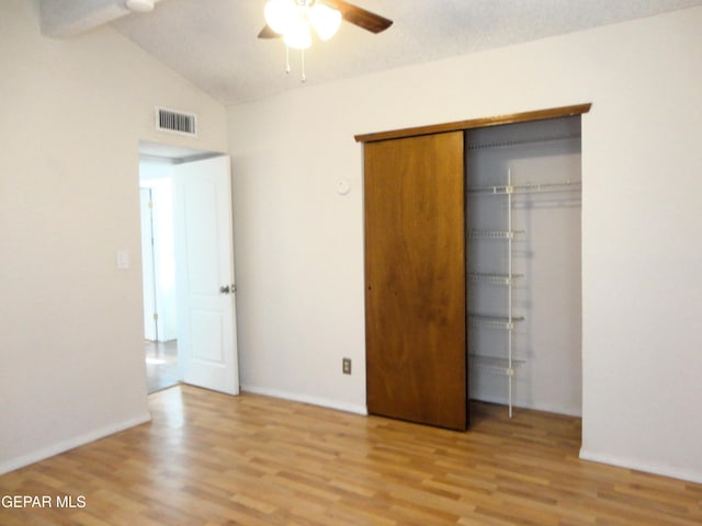 unfurnished bedroom with vaulted ceiling, a closet, visible vents, and light wood-style floors