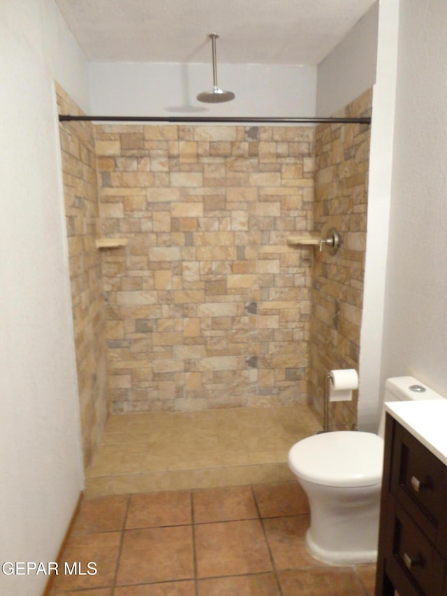 full bath with a tile shower, vanity, and toilet