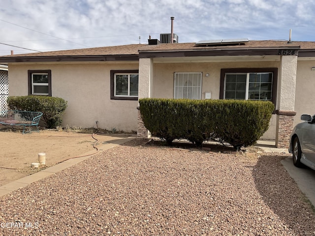 view of side of property with roof mounted solar panels, stucco siding, and roof with shingles