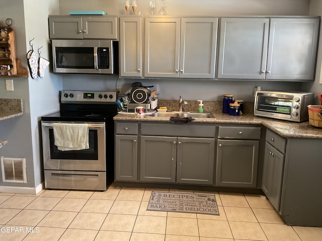 kitchen featuring visible vents, appliances with stainless steel finishes, gray cabinets, and a sink