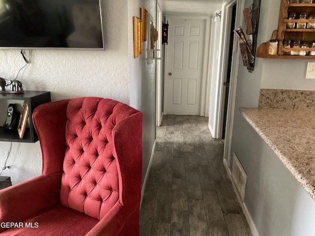 hall with baseboards, visible vents, a textured wall, stairway, and wood finish floors